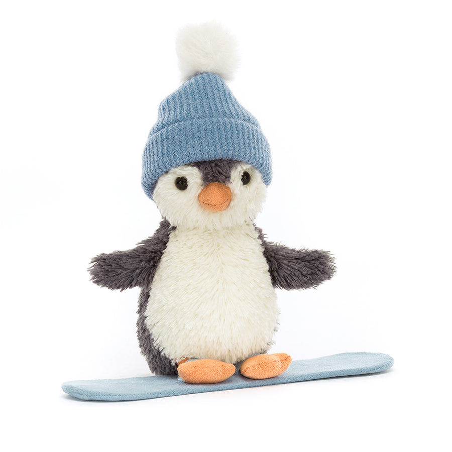Plush penguin wearing a blue knit hat standing on a snowboard