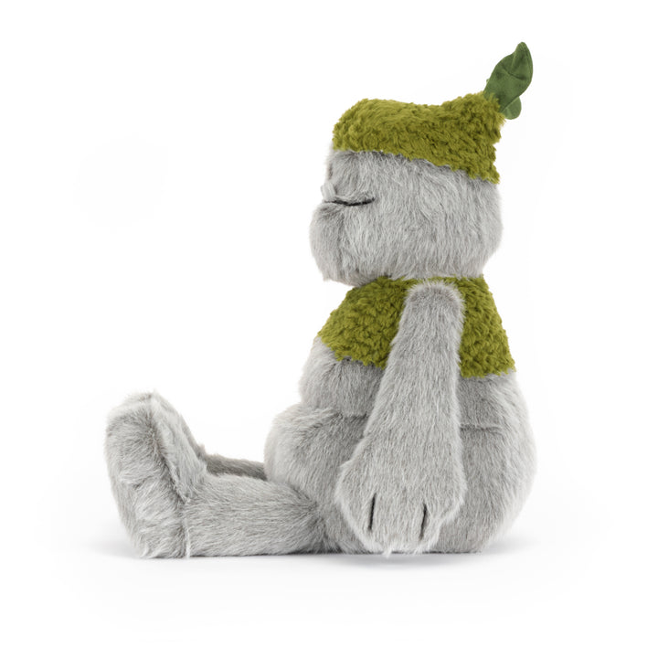 Rockleton Jellycat plush with soft gray fur, moss green accents, leafy sprout on its head, oversized feet, and a friendly embroidered smile sitting on a white background. Side view facing left