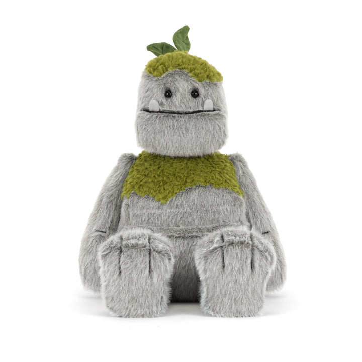 Rockleton Jellycat plush with soft gray fur, moss green accents, leafy sprout on its head, oversized feet, and a friendly embroidered smile sitting on a white background.