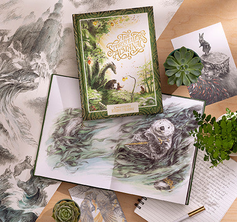 Illustrated book with nature-themed cover on a wooden surface with other art prints and plants.