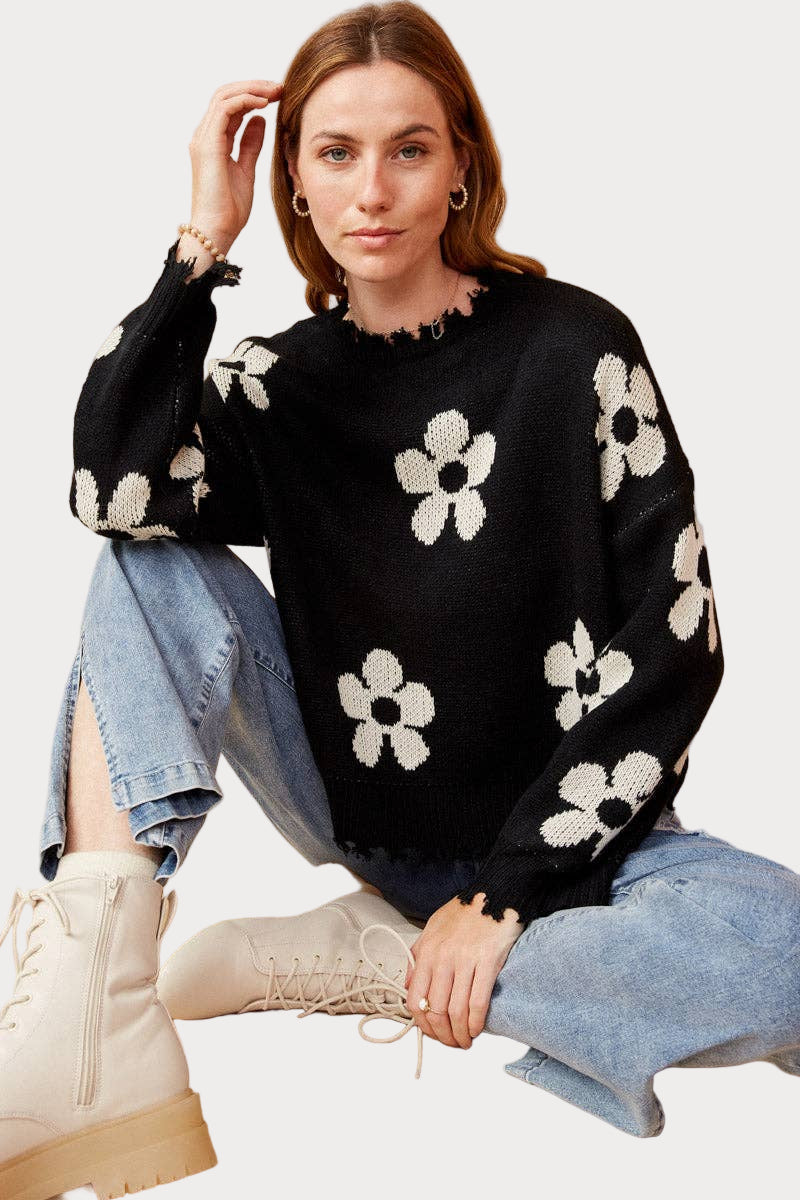 Women wearing black distressed floral pullover sweater with cream blooms—modern boho outfit, available in sizes S–3X.
