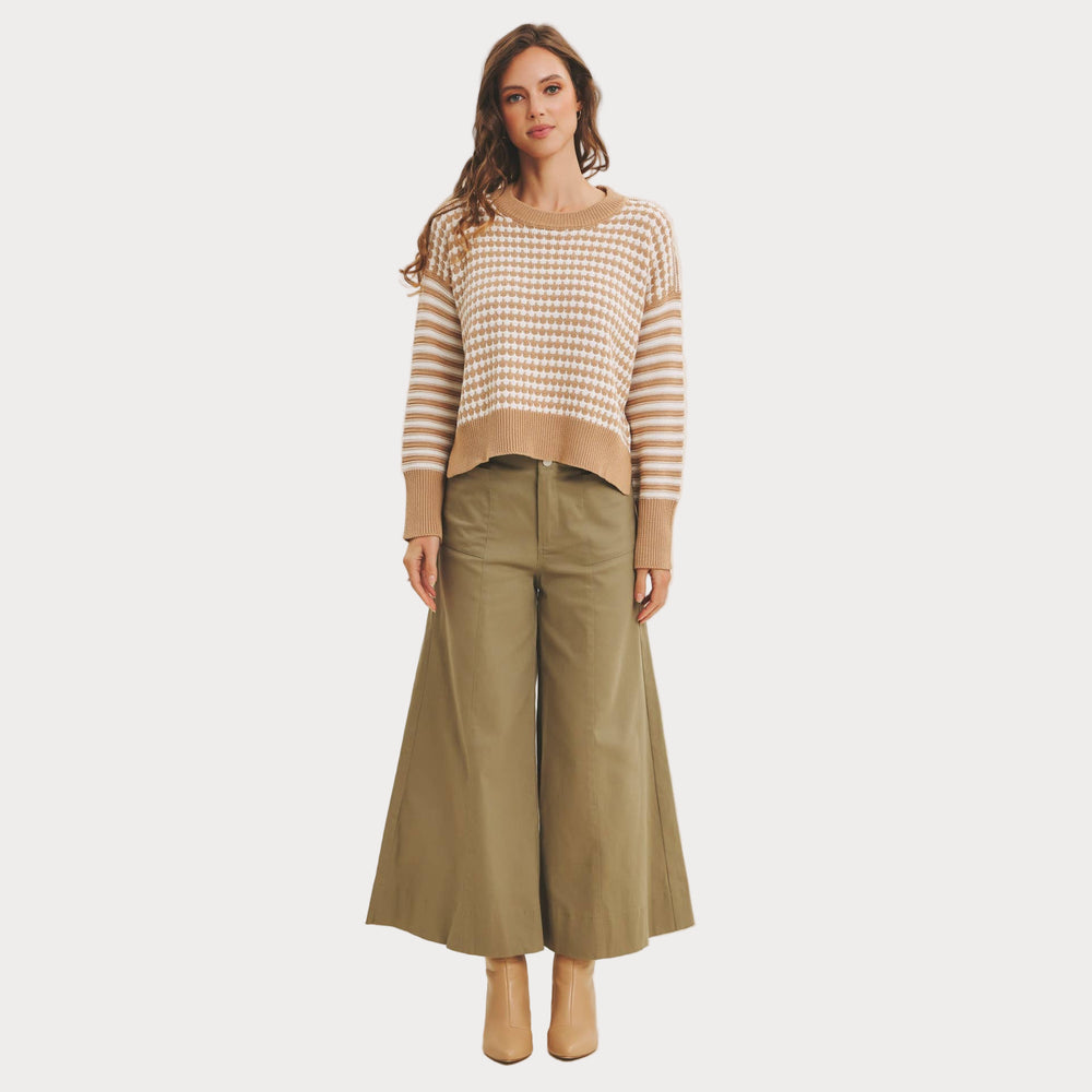 Woman wearing a striped sweater and wide-leg pants on a white background