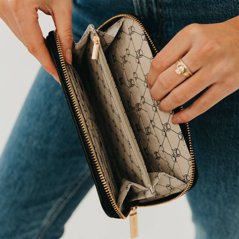 Person holding an open wallet with a patterned interior, wearing a gold ring.
