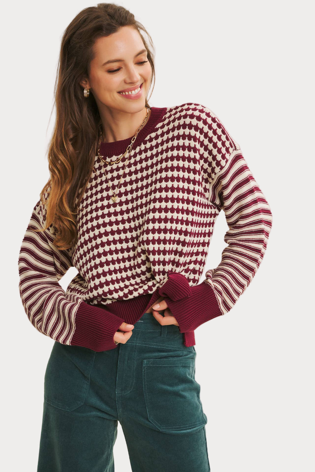 Woman wearing a red and white checkered sweater with green pants on a white background
