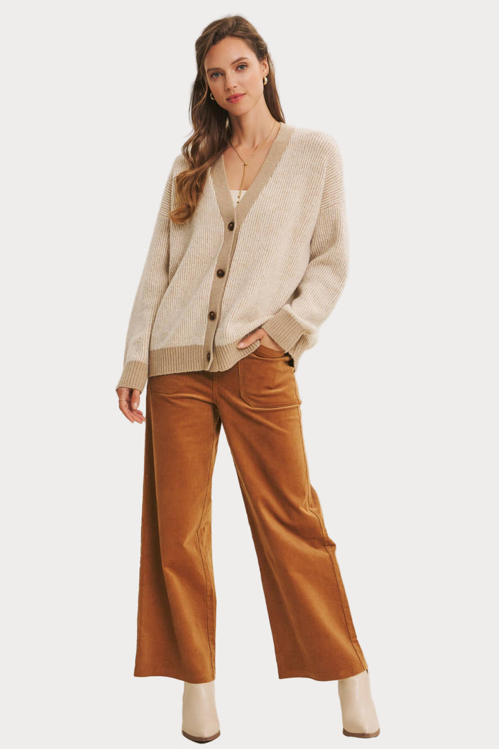 Woman wearing a beige cardigan and brown pants on a white background