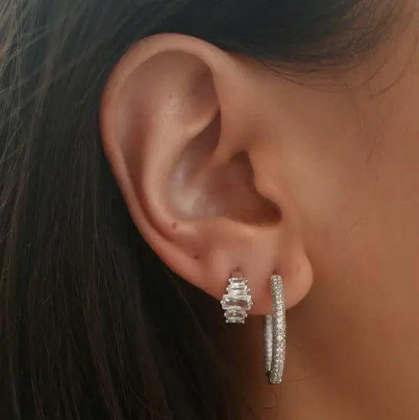 Close-up of an ear wearing silver hoop earrings with a blurred background