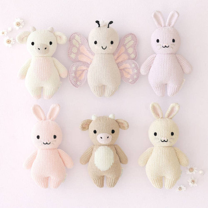 Set of six knitted toys in various animal shapes and colors on a light pink background