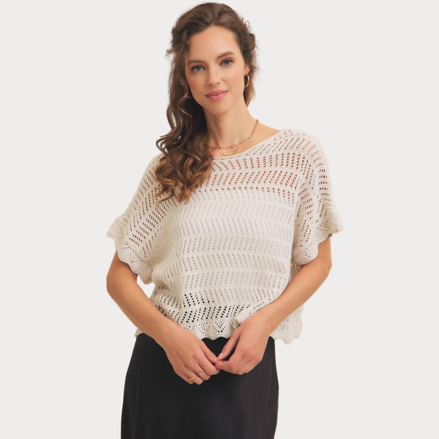 Woman wearing a white crochet top on a plain background