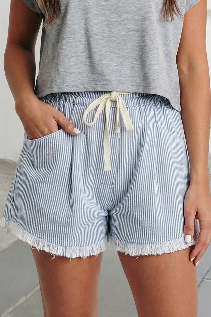 Person wearing blue and white striped shorts with a gray top on a light background