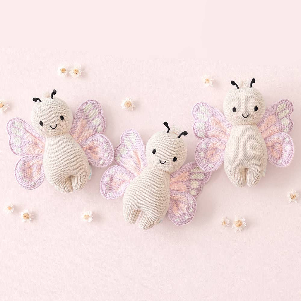 Three knitted butterfly toys on a pink background