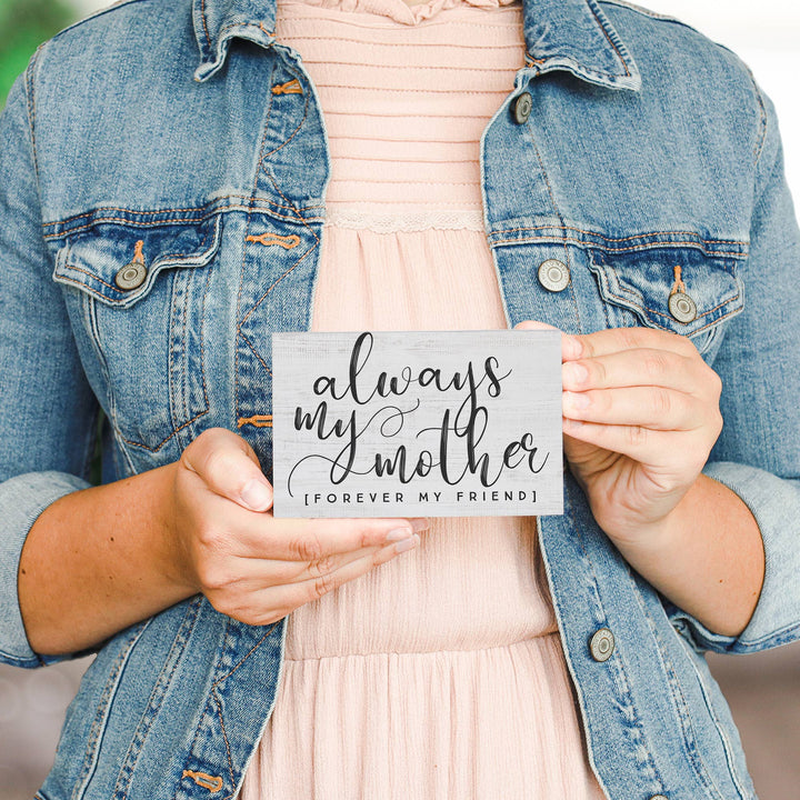 Person holding a sign with 'always my mother, forever my friend' text