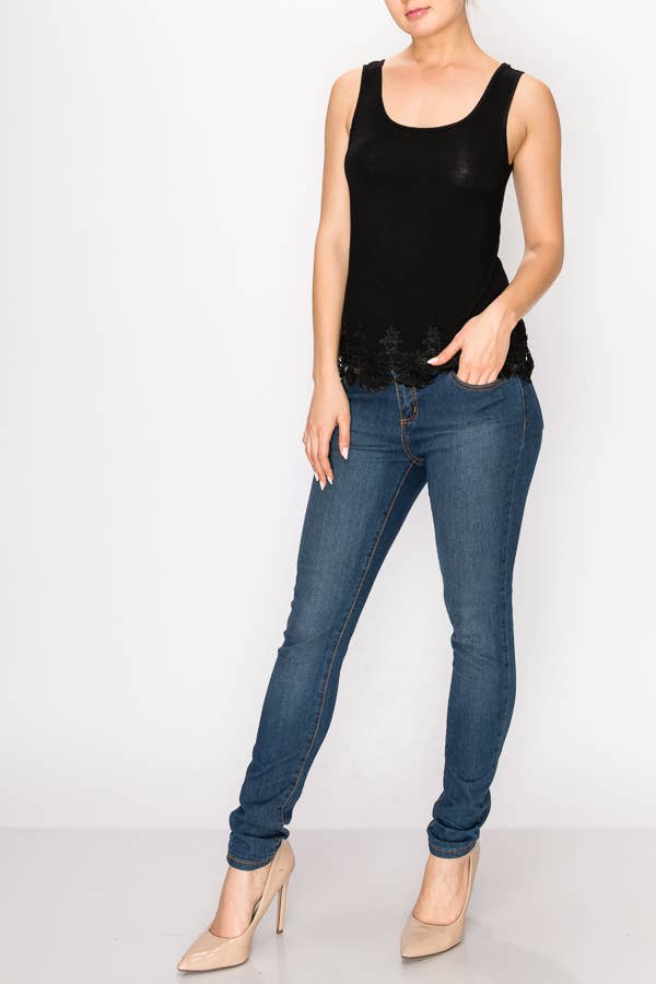 A model is shown from the torso up wearing a black scoop-neck tank top. The bottom hem is detailed with a delicate, scalloped black lace trim. She is wearing it with medium-wash blue jeans.

