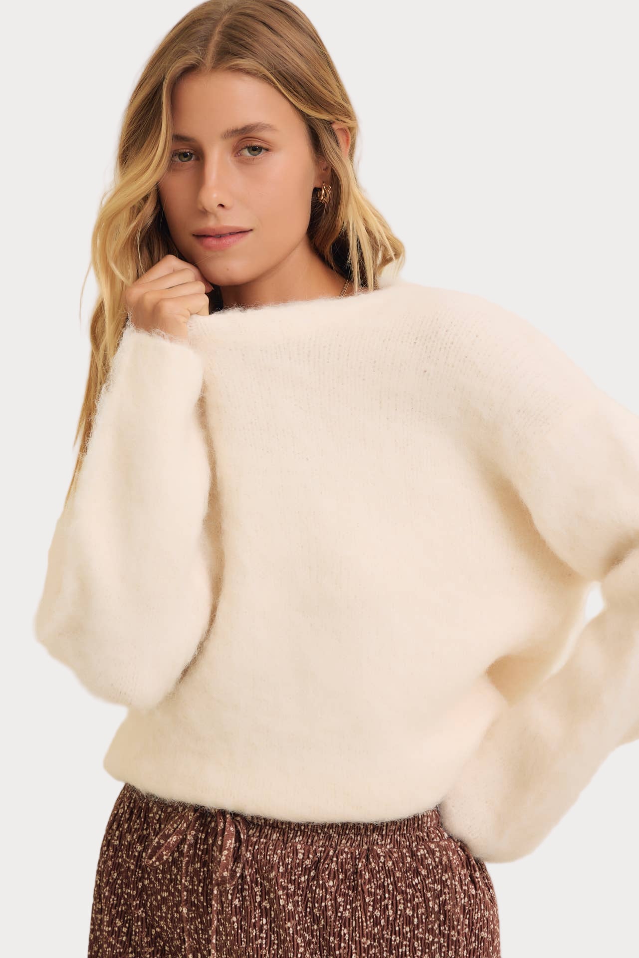 Woman wearing a cream sweater on a white background