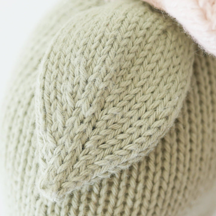 Close-up of a knitted green leaf with a textured pattern on a light background