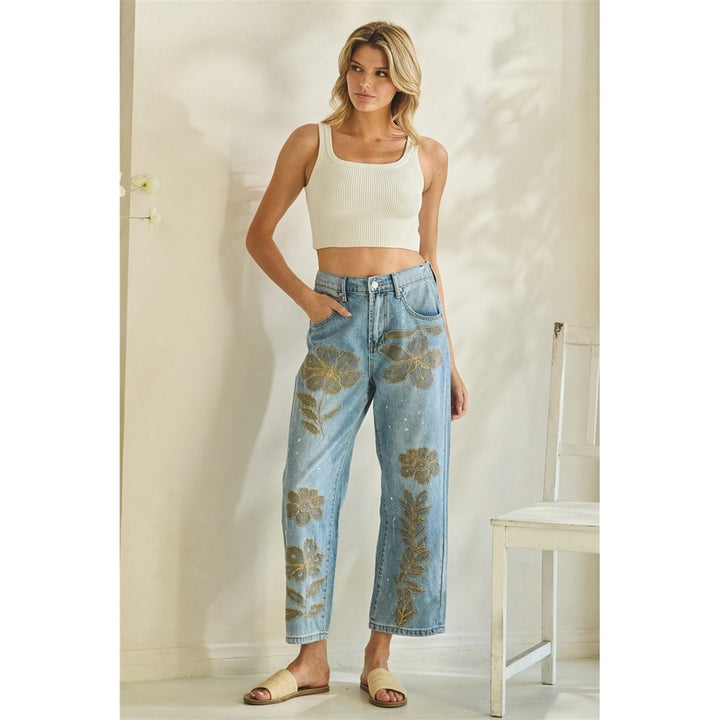Woman wearing floral jeans and a white top in a minimalistic room.