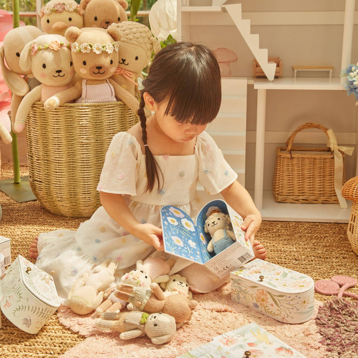 Child playing with knitted toys and a book in a cozy indoor setting