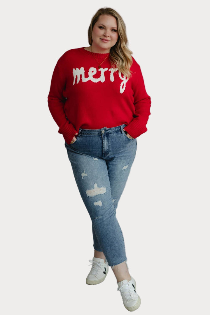 Plus size model wearing a red sweater with 'merry' text against a neutral background