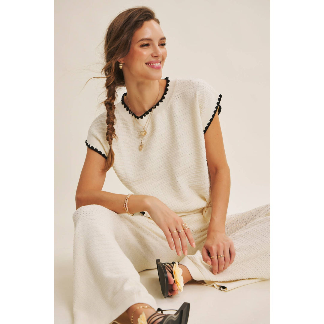 Cream textured sweater top with black whipstitch trim