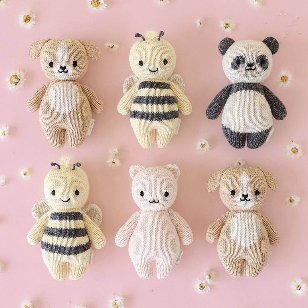 Set of six knitted toys on a pink background with white flowers.