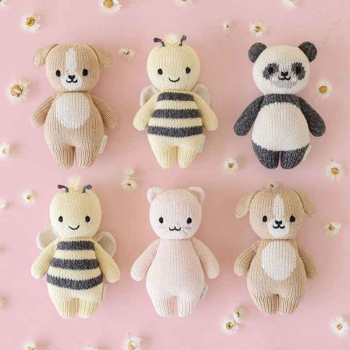 Set of six knitted toys on a pink background with white flowers.