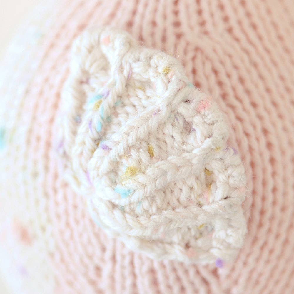 Close-up of a knitted plush fin white with colorful specks on a pink seahorse body
