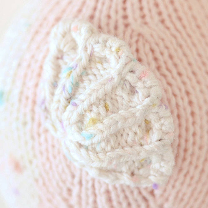 Close-up of a knitted plush fin white with colorful specks on a pink seahorse body