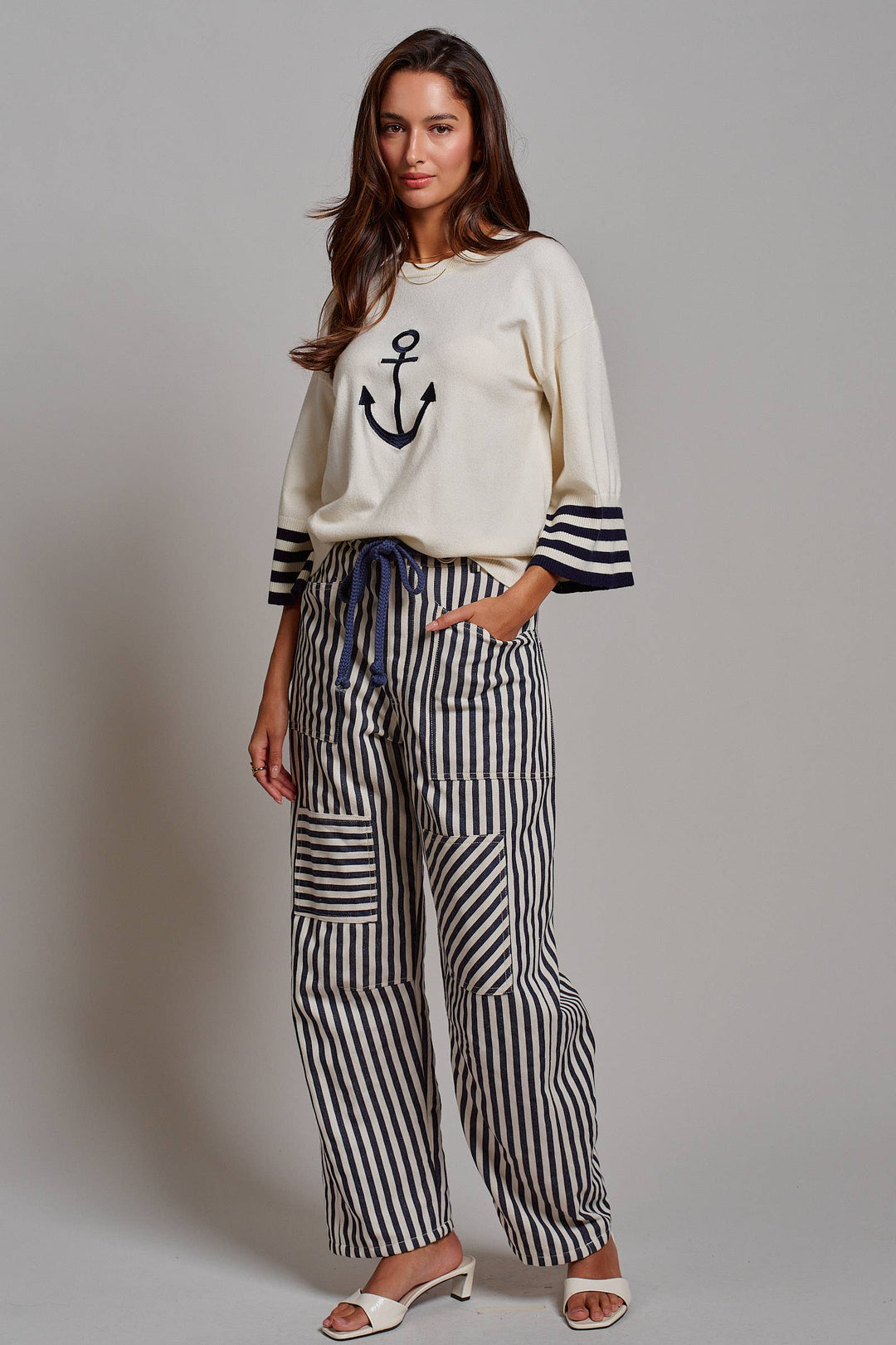 Woman wearing navy and ivory railroad stripe utility pants with oversized patch pockets, braided drawstring waist, and relaxed straight-leg fit.