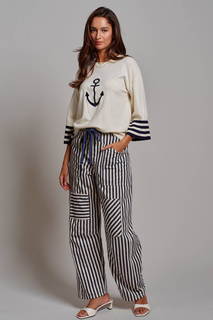 Woman wearing navy and ivory railroad stripe utility pants with oversized patch pockets, braided drawstring waist, and relaxed straight-leg fit.