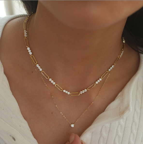 gold plated chain necklace with cubic zirconia accents along links worn by model layered with another necklace