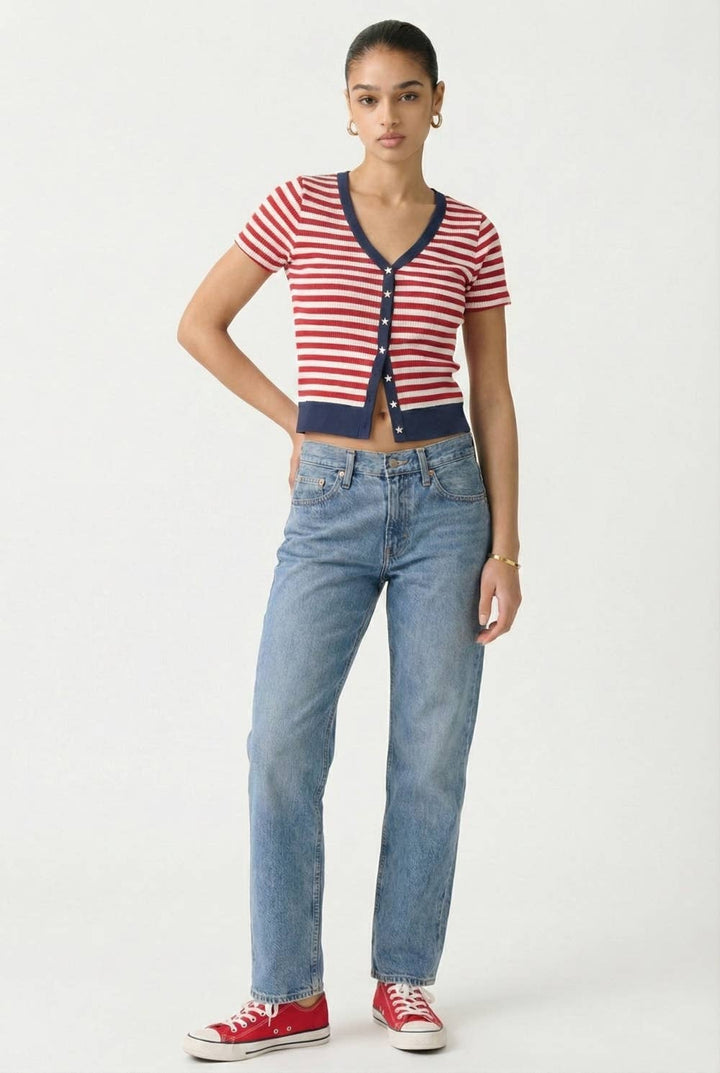 Woman wearing a red, white striped cardigan with navy trim & white star buttons and red sneakers on a white background