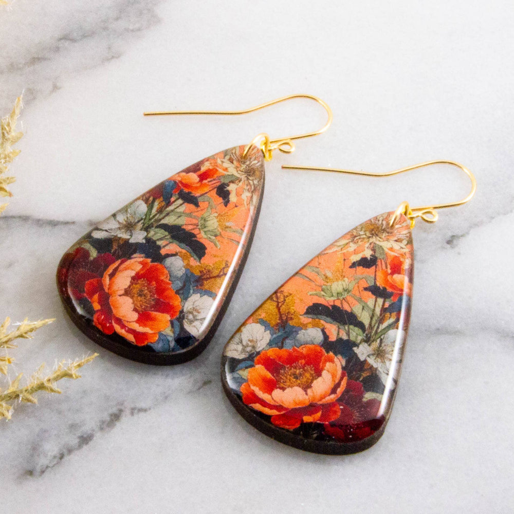 Teardrop-shaped floral earrings on a marble surface