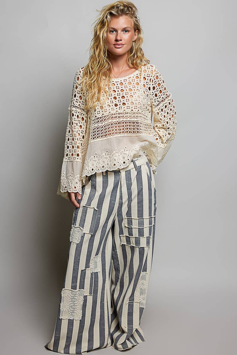 Model wearing The Briar Rose Crochet Blouse featuring intricate open crochet, embroidered eyelet cotton panels, long bell sleeves, and a relaxed bohemian silhouette in ivory.