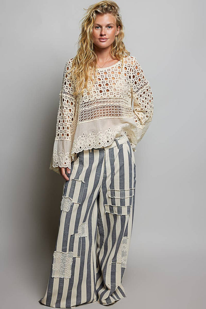 Model wearing The Briar Rose Crochet Blouse featuring intricate open crochet, embroidered eyelet cotton panels, long bell sleeves, and a relaxed bohemian silhouette in ivory.