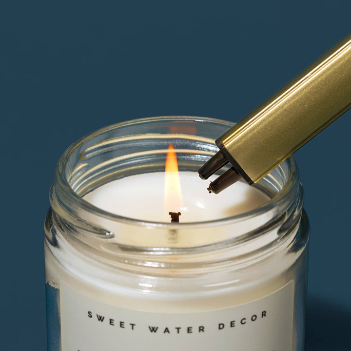 Candle being lit with a rechargable lighter, featuring 'Sweet Water Decor' branding.