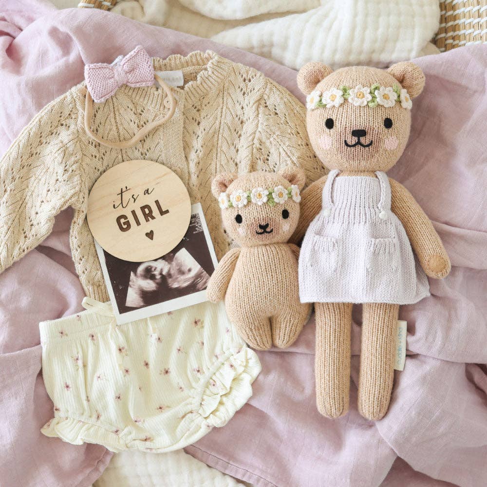 Knitted baby outfit with teddy bears and baby shower card on a pink blanket