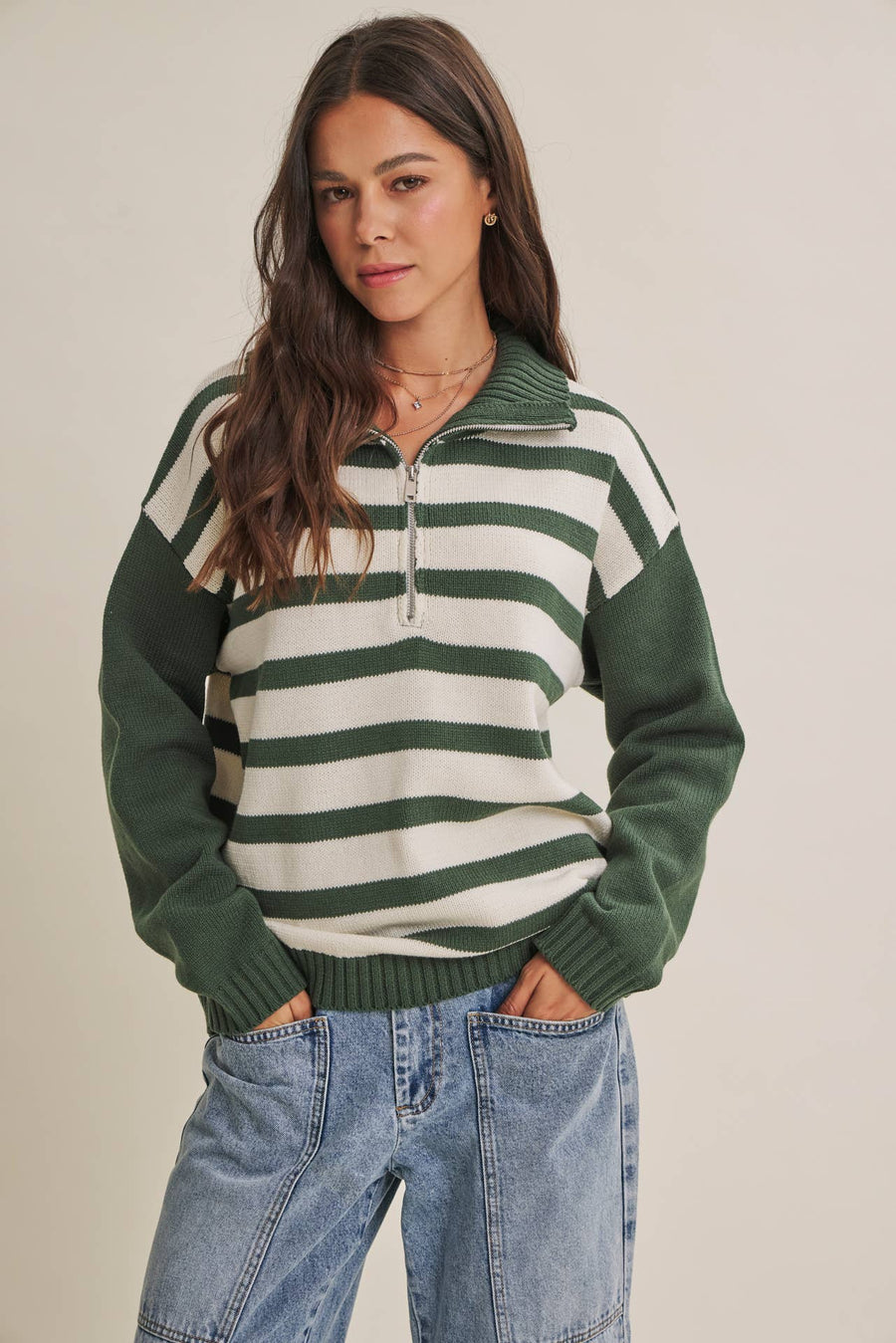 Woman wearing The Emerson evergreen and cream striped half-zip sweater with relaxed blue jeans