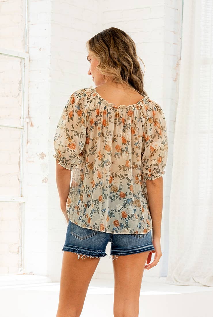 Woman wearing lightweight floral blouse with ruffle neckline and short sleeves
