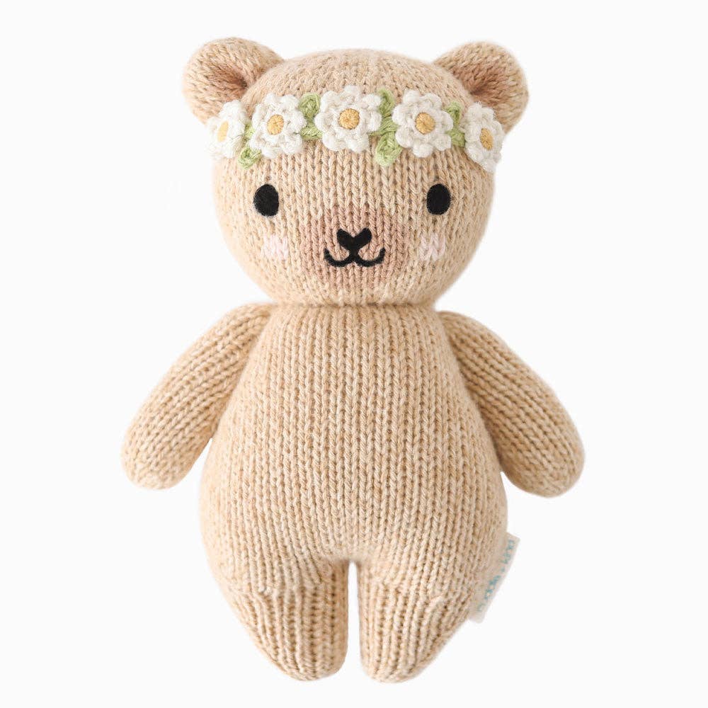 Knitted teddy bear with a flower crown on a white background