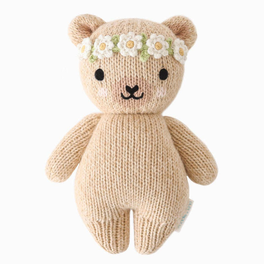 Knitted teddy bear with a flower crown on a white background