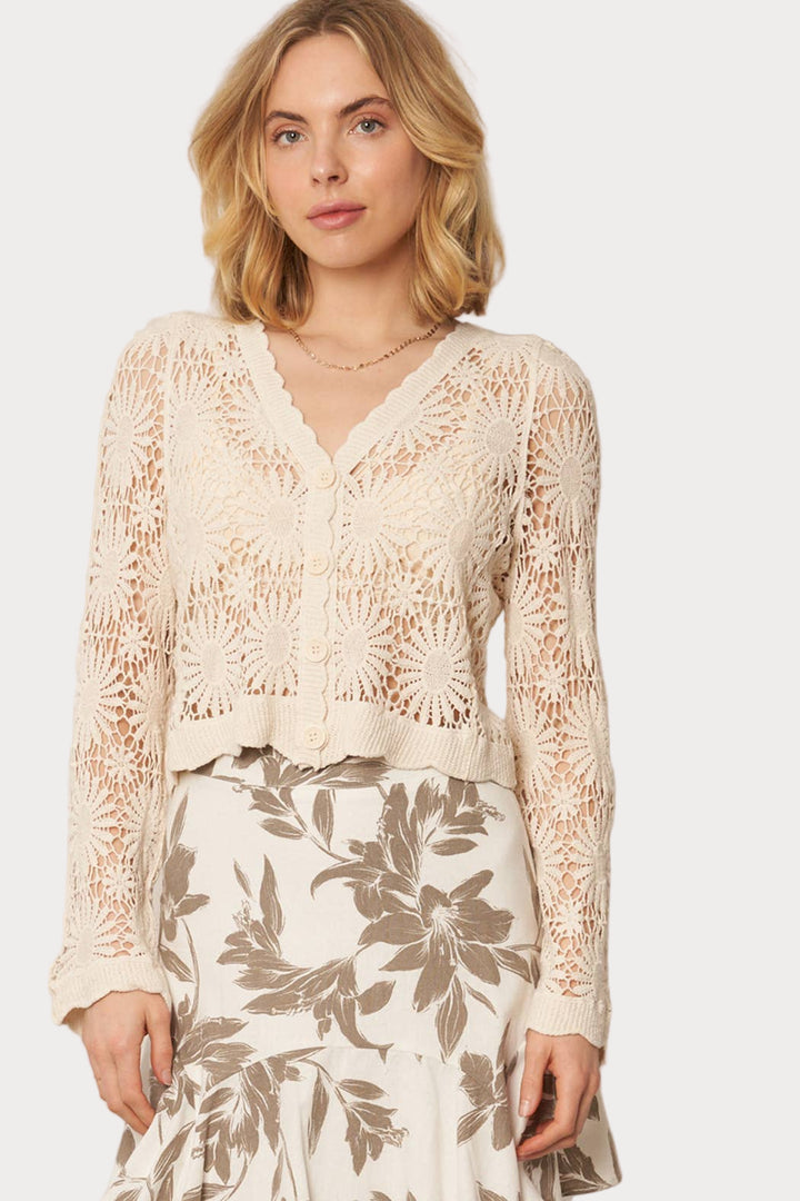 Woman wearing a beige lace top and floral skirt on a white background
