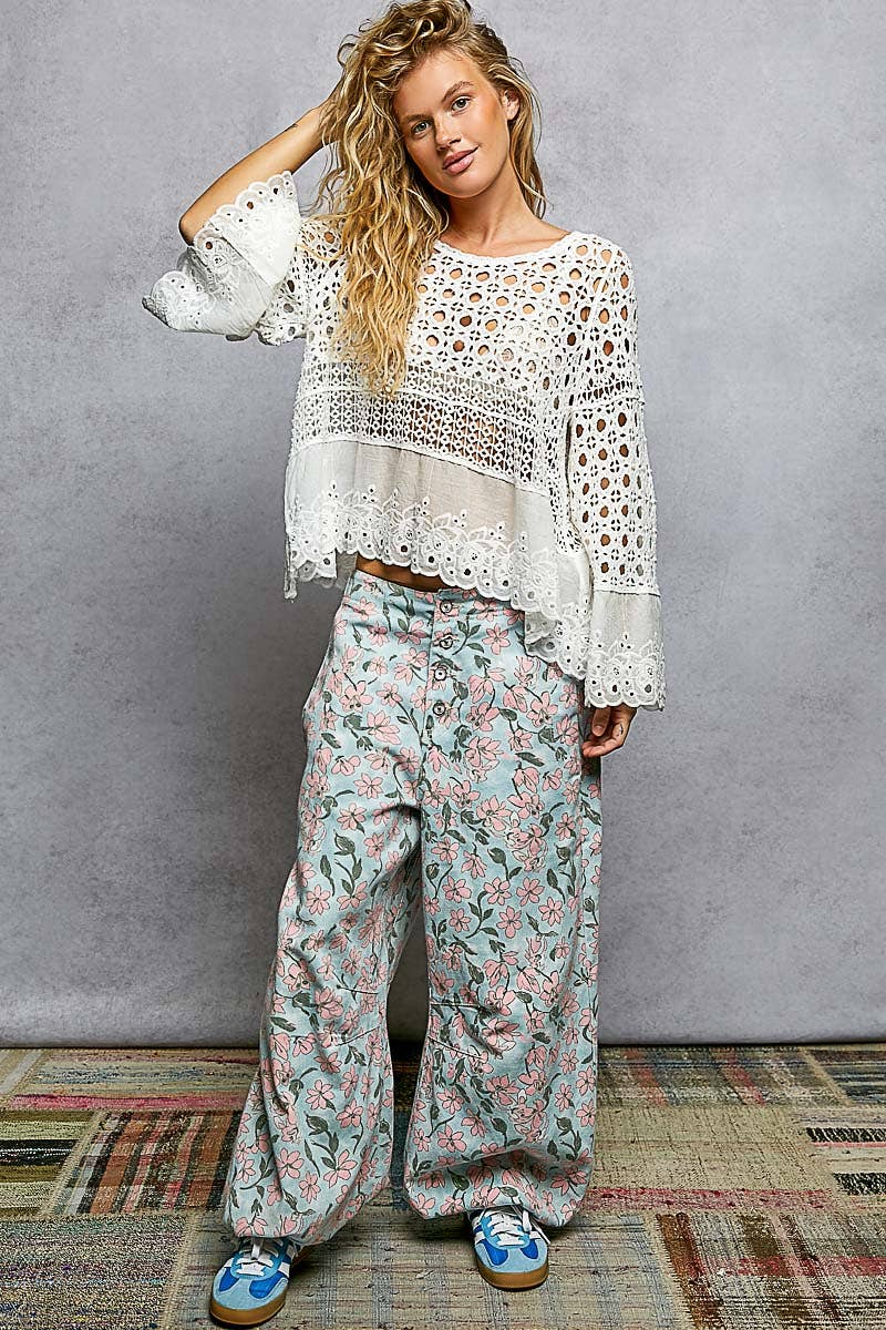 Model wearing The Briar Rose Crochet Blouse featuring intricate open crochet, embroidered eyelet cotton panels, long bell sleeves, and a relaxed bohemian silhouette in ivory.