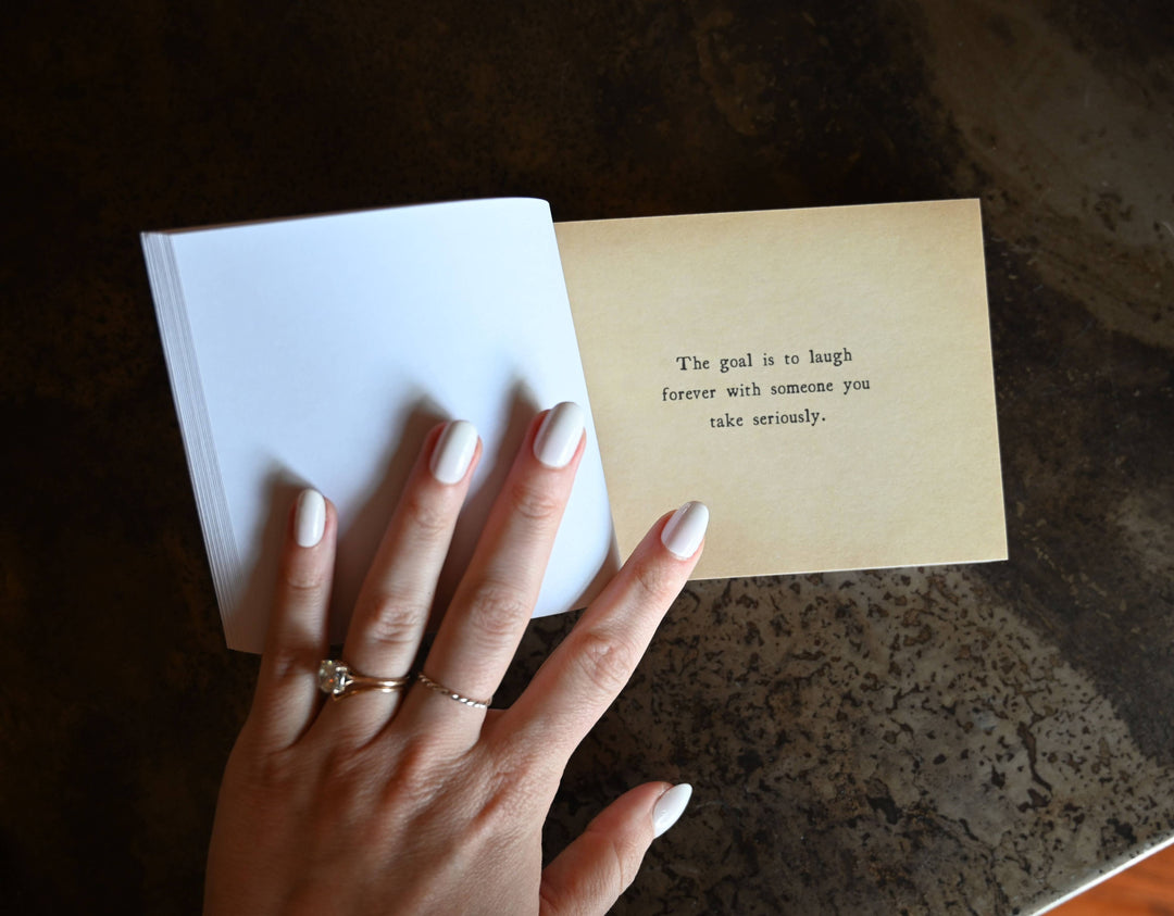 Hand holding a book with a quote on a textured surface