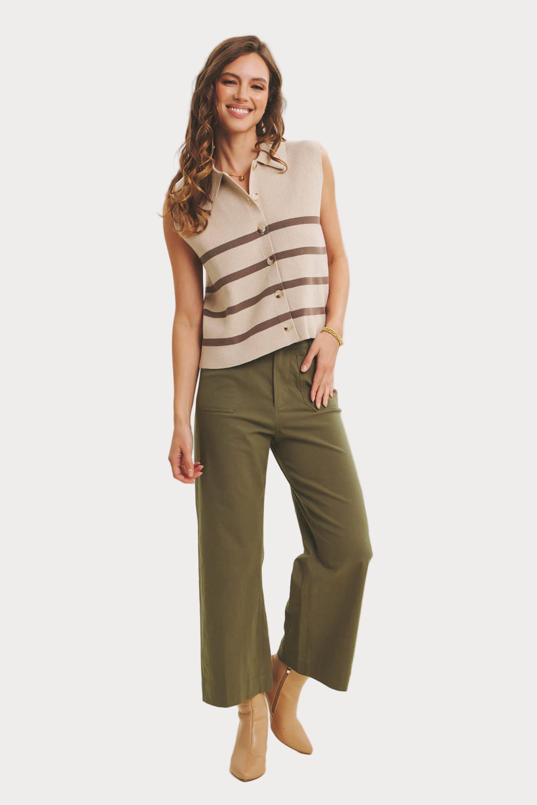 Woman wearing a sleeveless striped top and green pants on a beige background