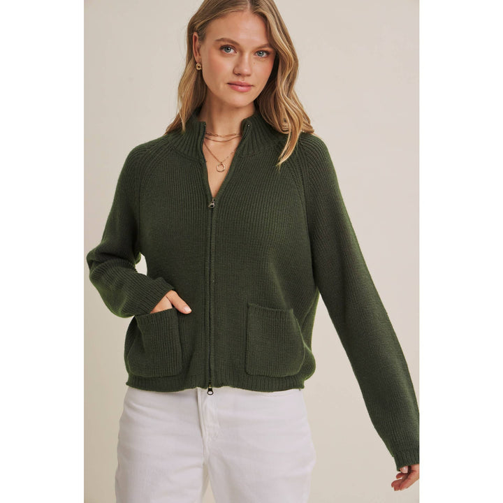 Woman wearing a green zip-up sweater against a neutral background