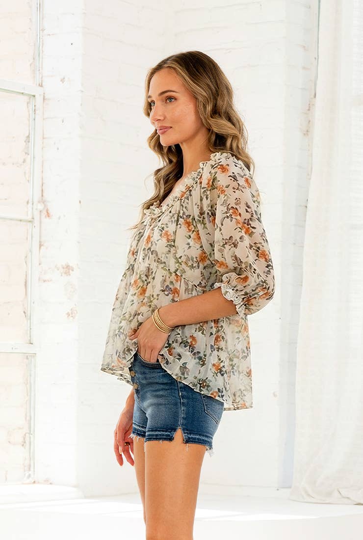 Woman wearing lightweight floral blouse with ruffle neckline and short sleeves