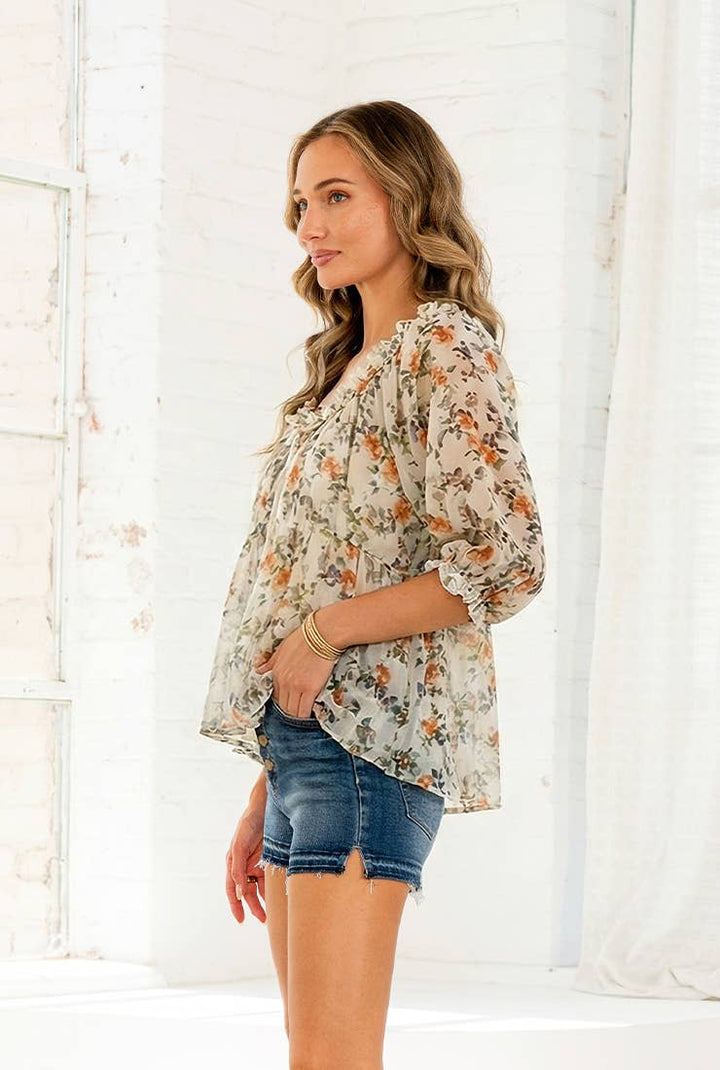 Woman wearing lightweight floral blouse with ruffle neckline and short sleeves