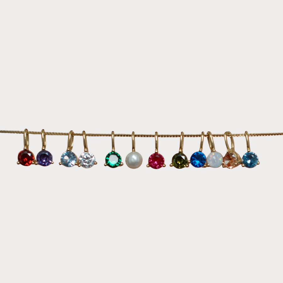 Gold birthstone charms in assorted gemstone colors and pearl, displayed on fine chain necklace