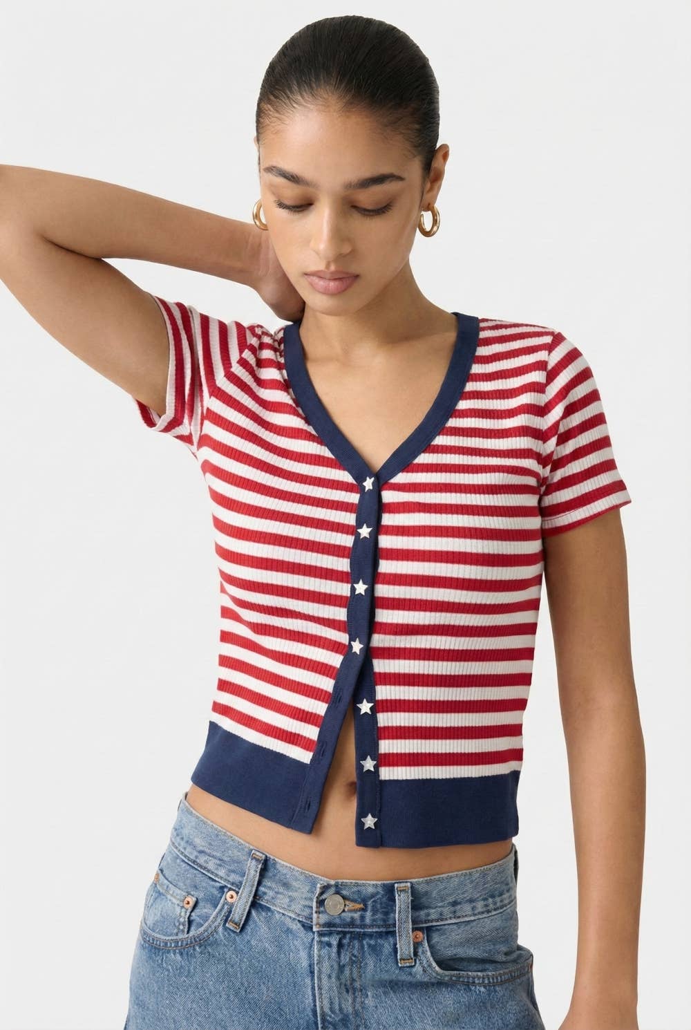 Woman wearing a red, white striped cardigan with navy trim & white star buttons on a white background