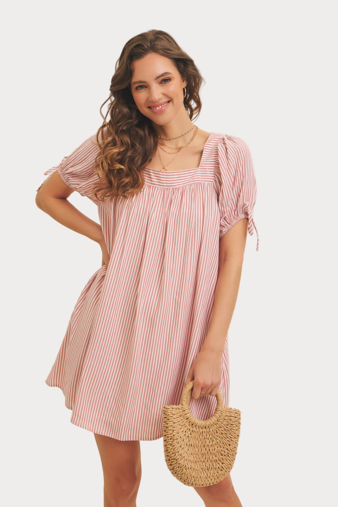 A woman wearing a square neck, striped flare mini dress with puff sleeves and a bow detail.