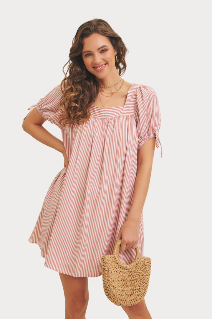 A woman wearing a square neck, striped flare mini dress with puff sleeves and a bow detail.